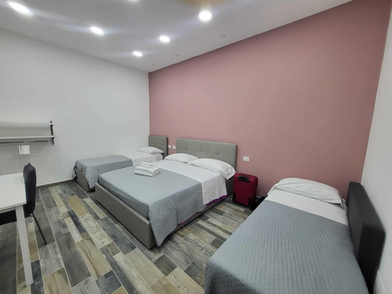 A hotel room with three beds, a desk, and a chair.