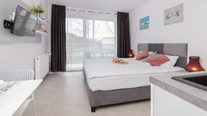 Habitación de hotel moderna con cama, escritorio, televisión y vistas al exterior.