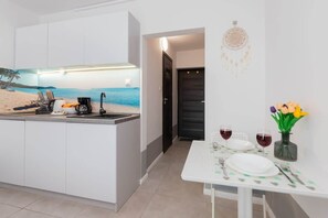 Uma cozinha moderna com um mural temático praiano, uma área de refeições com uma mesa posta para dois e um sonho-pescador na parede.