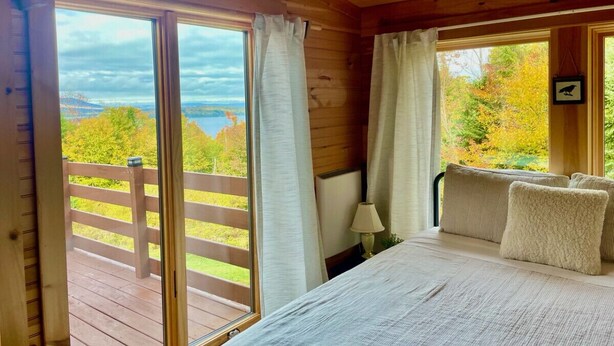 A wooden cabin bedroom with a bed, pillows, a nightstand, and a window with curtains. - Overlook Cabin - Lake/Mountain View*Pet Friendly*A/C*Washer/Dryer (Greenville)