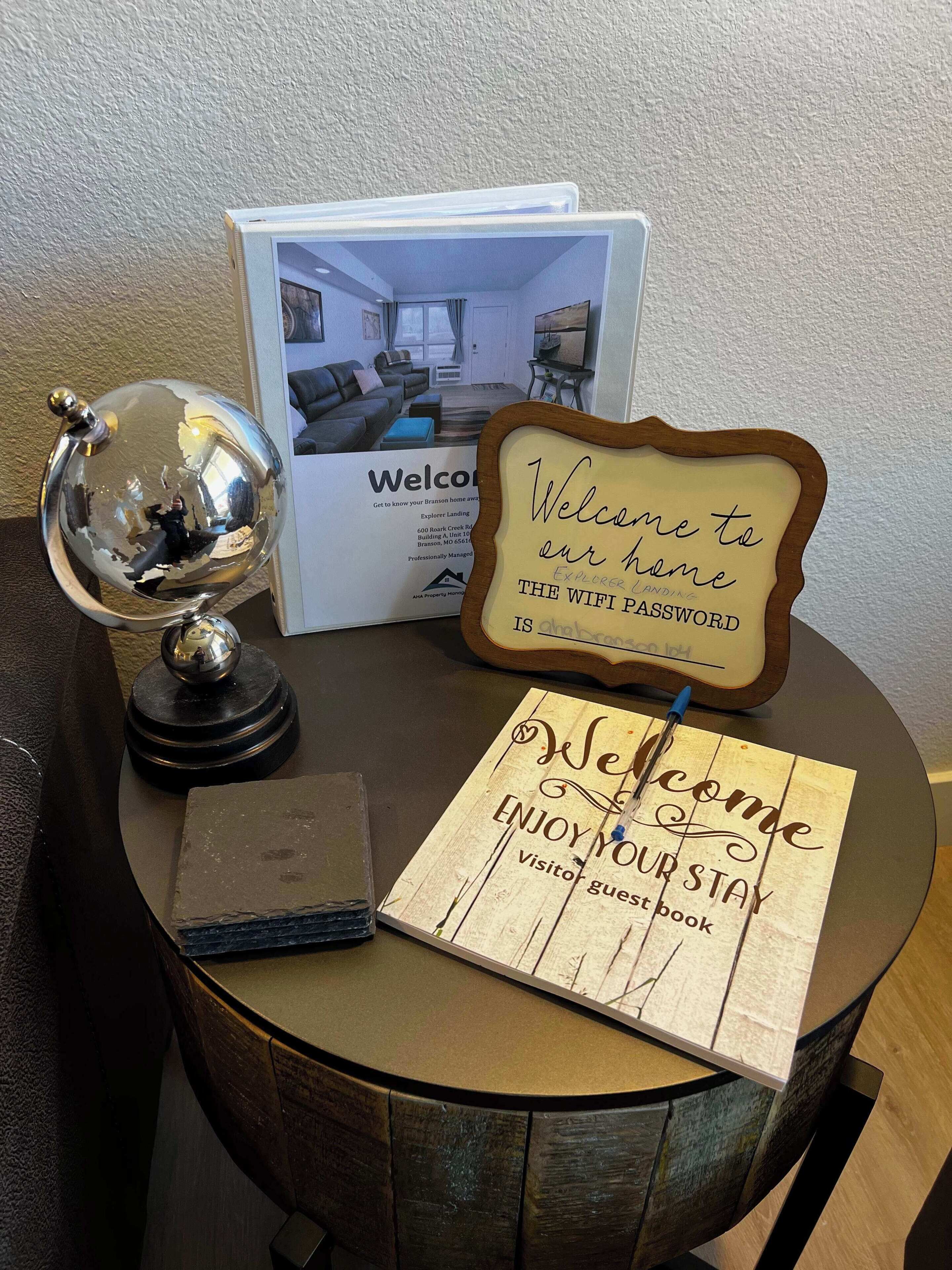 A welcome sign, a guest book, and a brochure on a table.