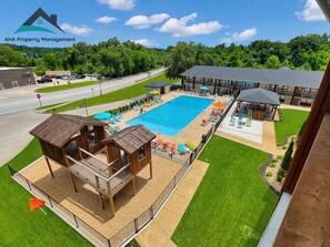 A pool area with a wooden deck, lounge chairs, and a gazebo. - 104-Ground level, close to convention center (Branson)