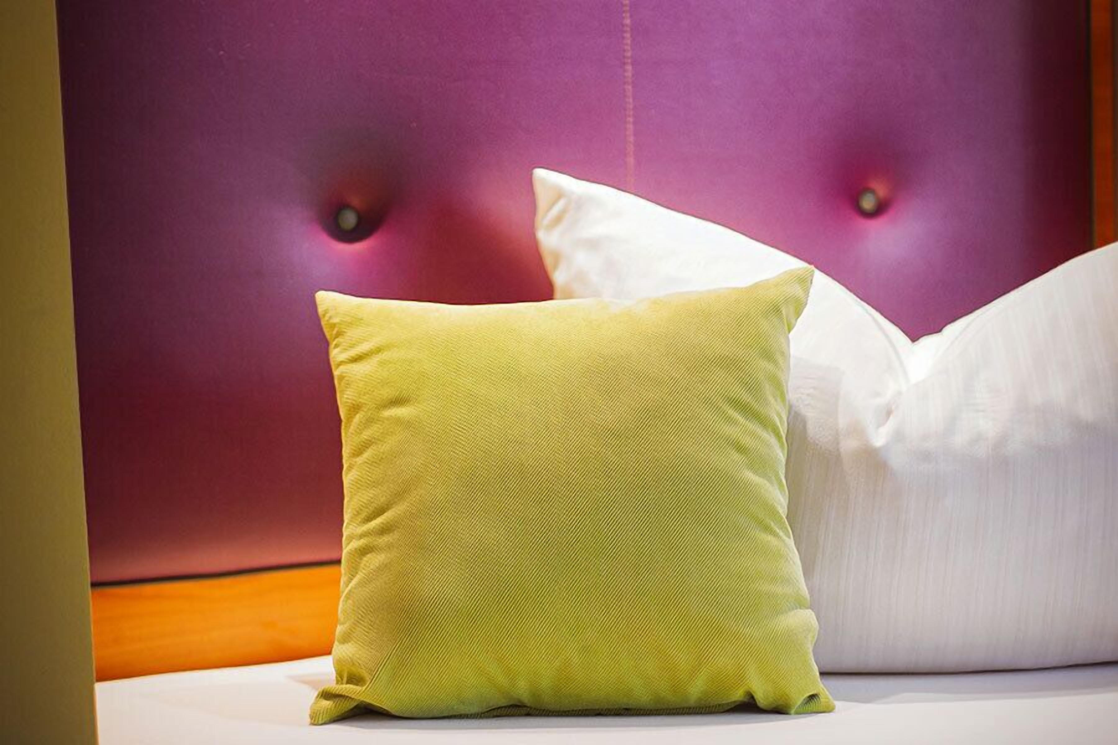 A bed with a tufted headboard and two pillows, one green and one white.