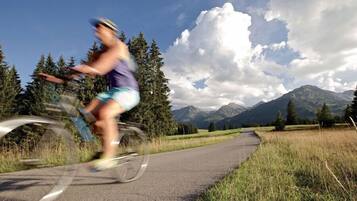 A cyclist on a paved path with a mountainous landscape in the background.