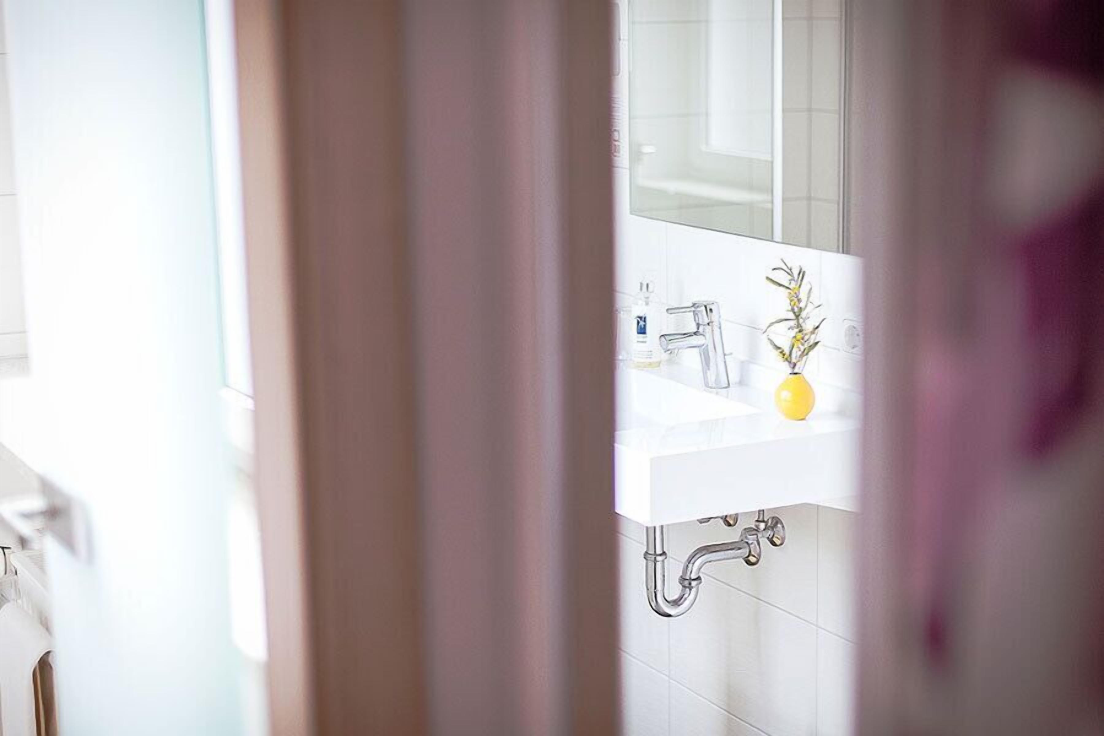 A bathroom with a white sink, a mirror, and a yellow soap dispenser.