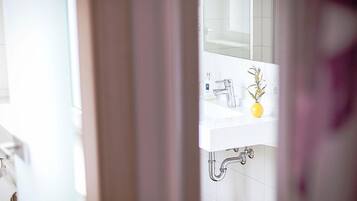 A bathroom with a white sink, a mirror, and a yellow soap dispenser.