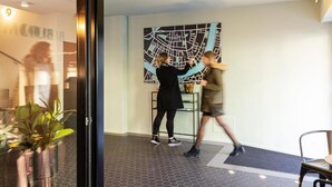 A modern interior with a large map on the wall, a glass door entrance, and a seating area with a chair. - BLOOM Boutique Hotel & Lounge Basel (Basel)