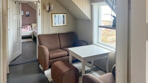 A cozy room with a sofa, a small table, and a window with a view of the outdoors. - Nice home in Smøla with house sea view (Smøla)