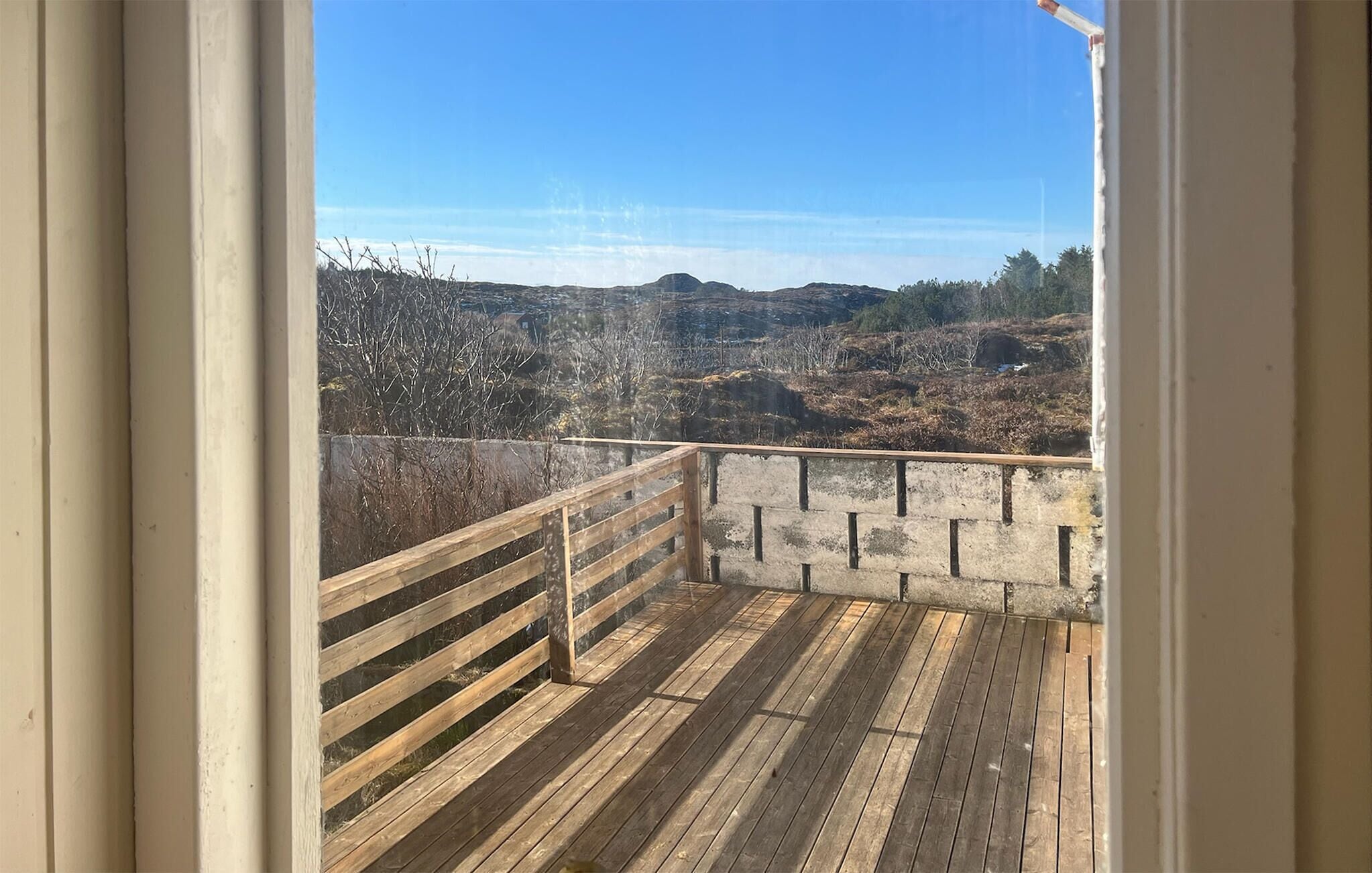 Una terrazza in legno con ringhiera metallica che si affaccia su un paesaggio collinare.