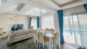 Uma sala de estar moderna com sofá, mesa de jantar, cadeiras e televisão.