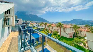 Zona residencial com casas modernas, piscina e montanha ao fundo.