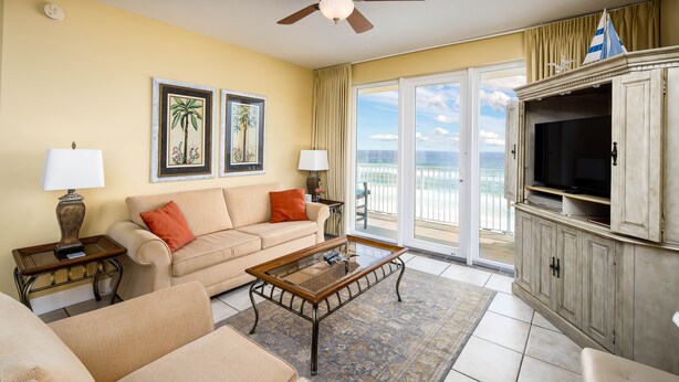 A living room with a sofa, coffee table, and TV, a balcony with a view of the ocean, and a sailboat decoration. - SDN 504: Vacation Vibe - Spectacular Corner Unit with MARVELOUS Beach Views! (Fort Walton Beach)