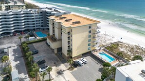 A multi-story hotel with a rooftop pool, a beach view, and a parking area. - SDN 504: Vacation Vibe - Spectacular Corner Unit with MARVELOUS Beach Views! (Fort Walton Beach)