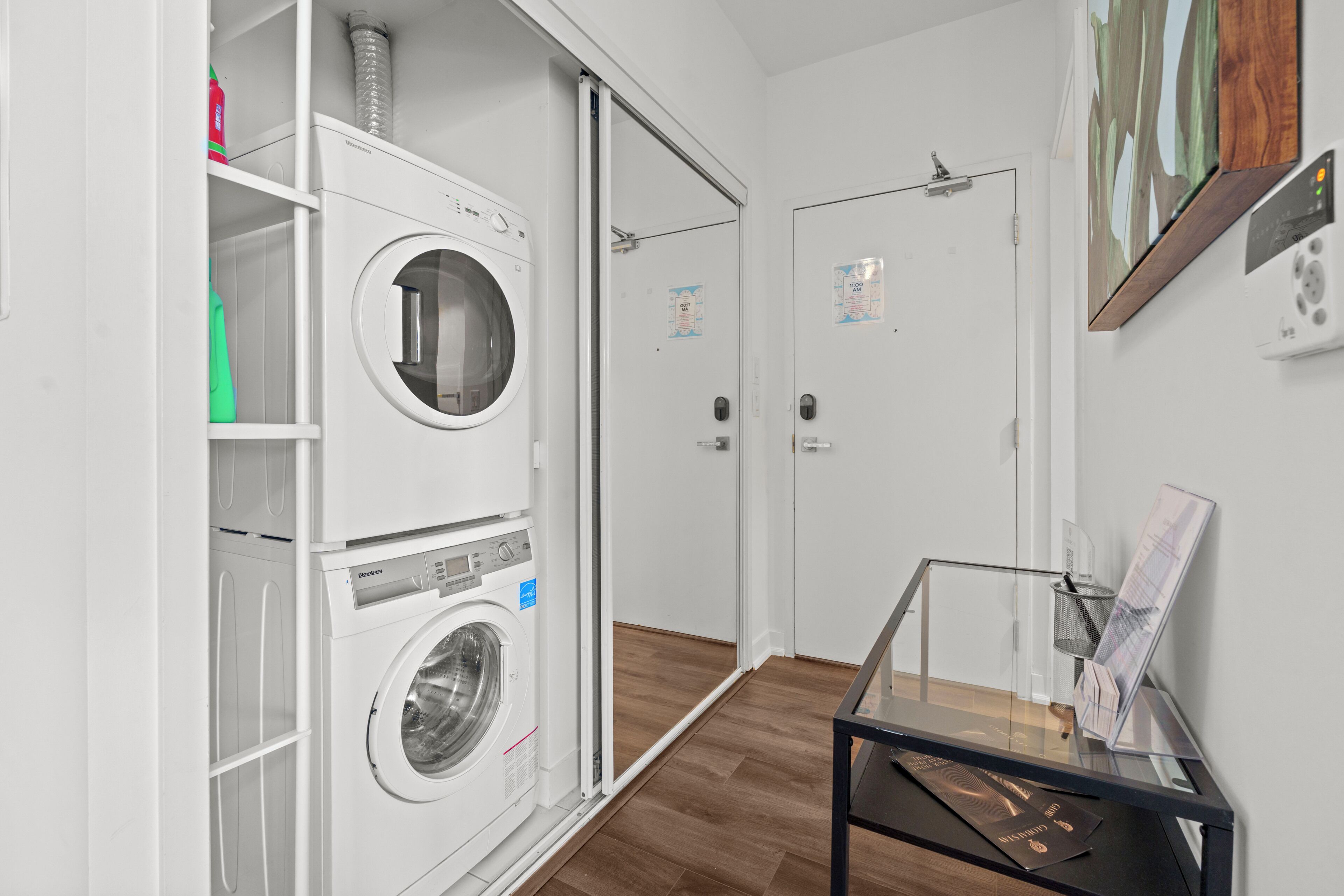 A laundry room with stacked washers and dryers, a glass display case, and a door with a poster.