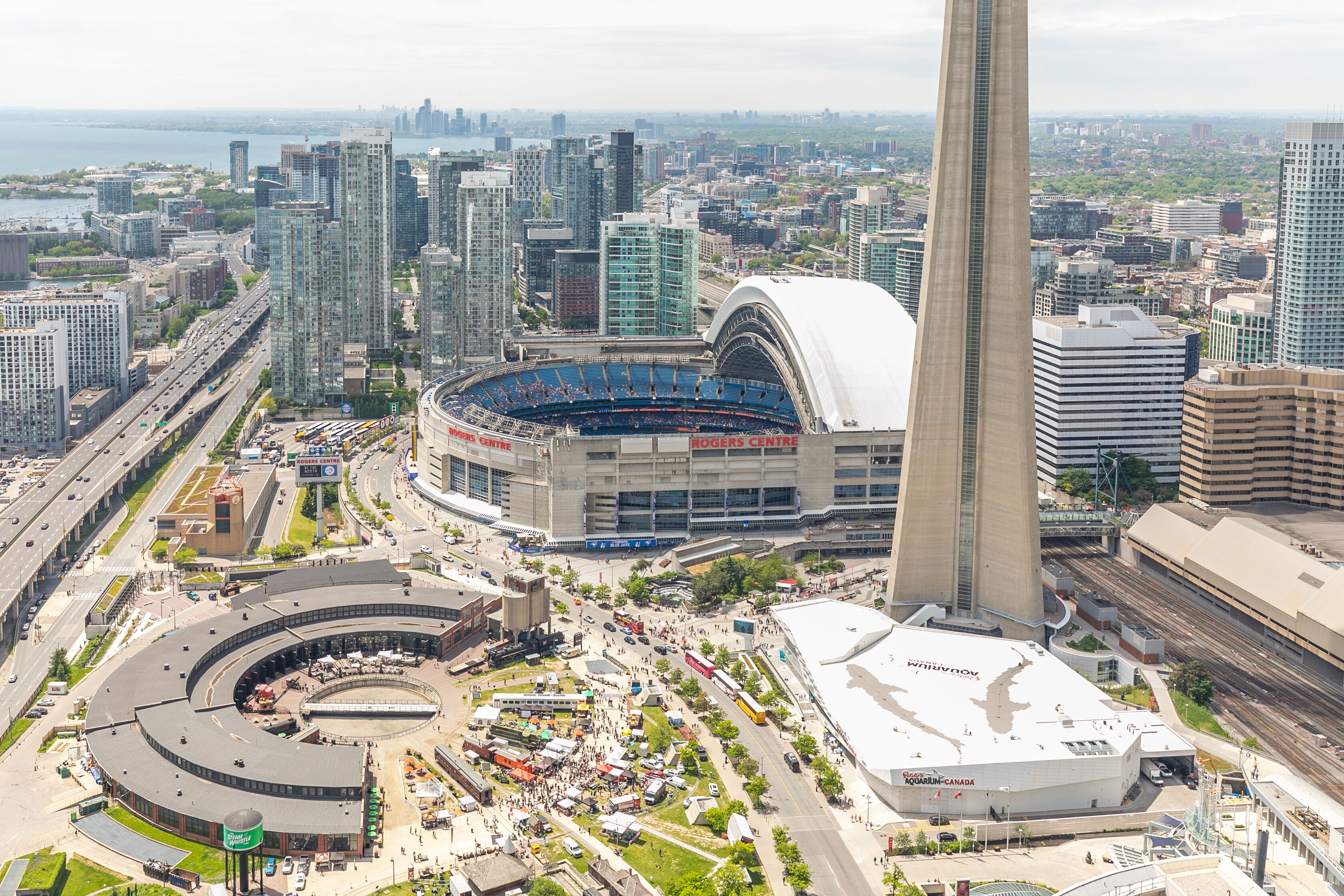 A stadium with a large central dome and a tall tower, surrounded by a cityscape with high-rise buildings.