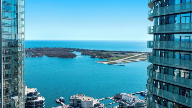 A high-rise building with a view of a large body of water and a distant shoreline. - York Suites Toronto (Toronto)