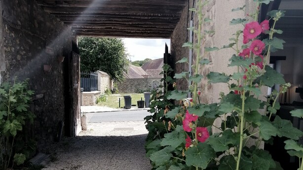 Un sendero de grava que conduce a la entrada de un edificio bajo un arco de madera.