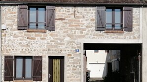 Edificio de piedra con un letrero con el número 9, una puerta con un portón metálico y un porche cubierto.