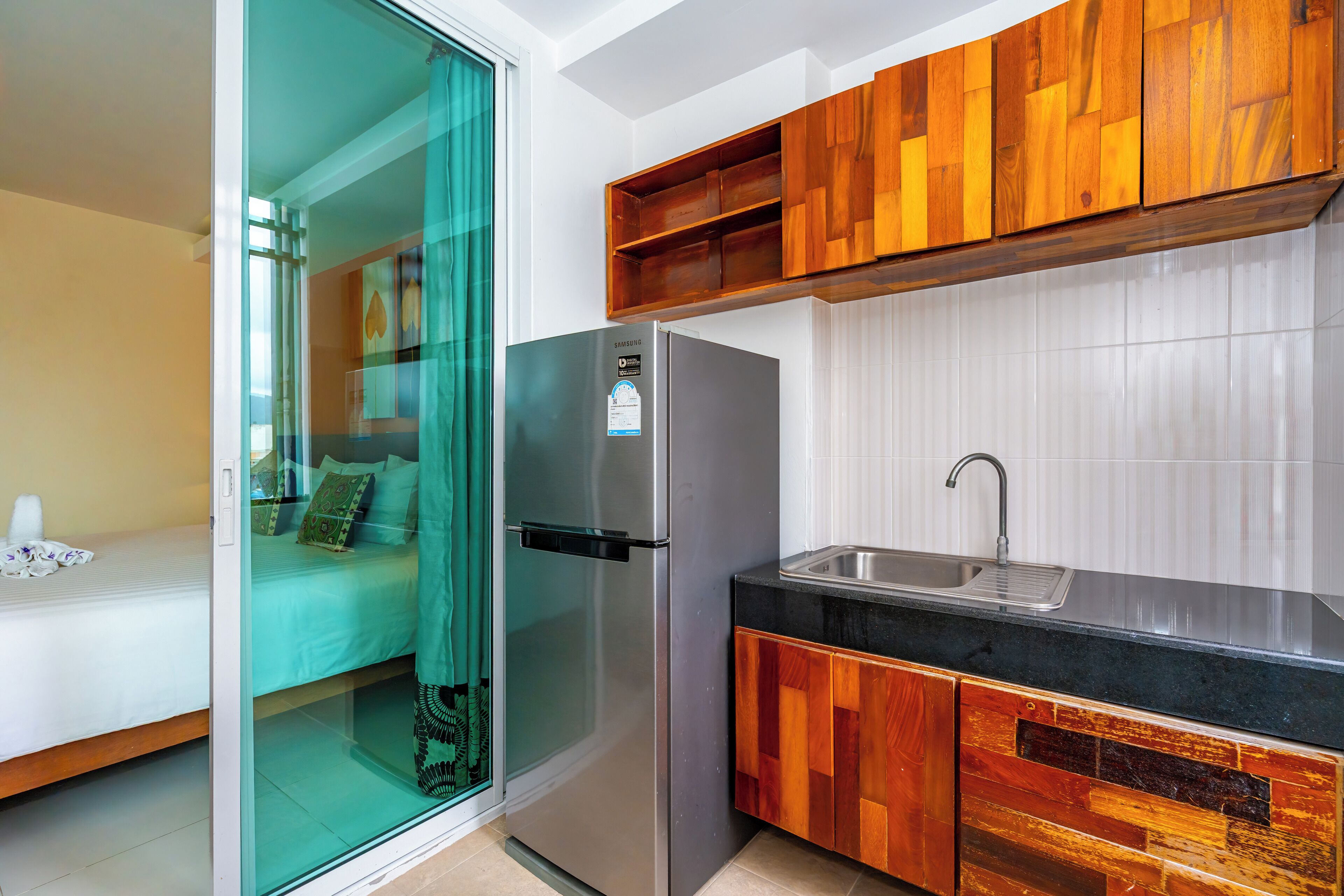 A compact kitchen with a refrigerator, a sink, and wooden cabinets.