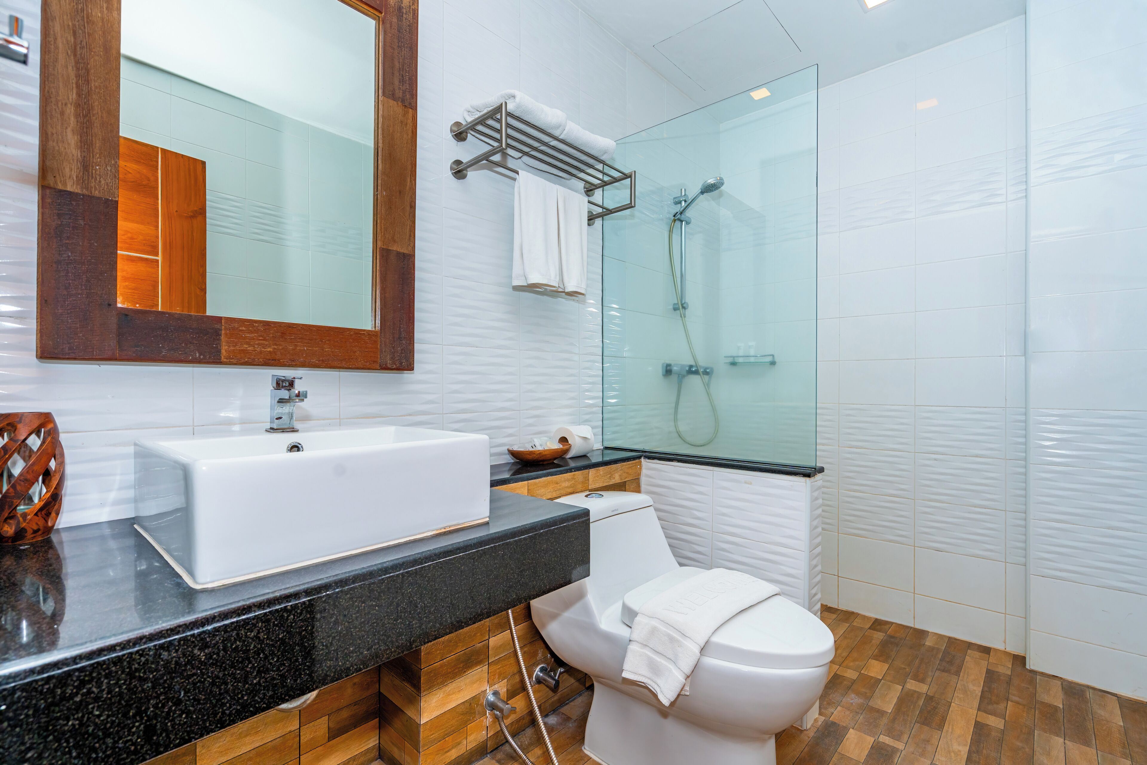 A modern bathroom with a white sink, a glass shower enclosure, and a wooden vanity.
