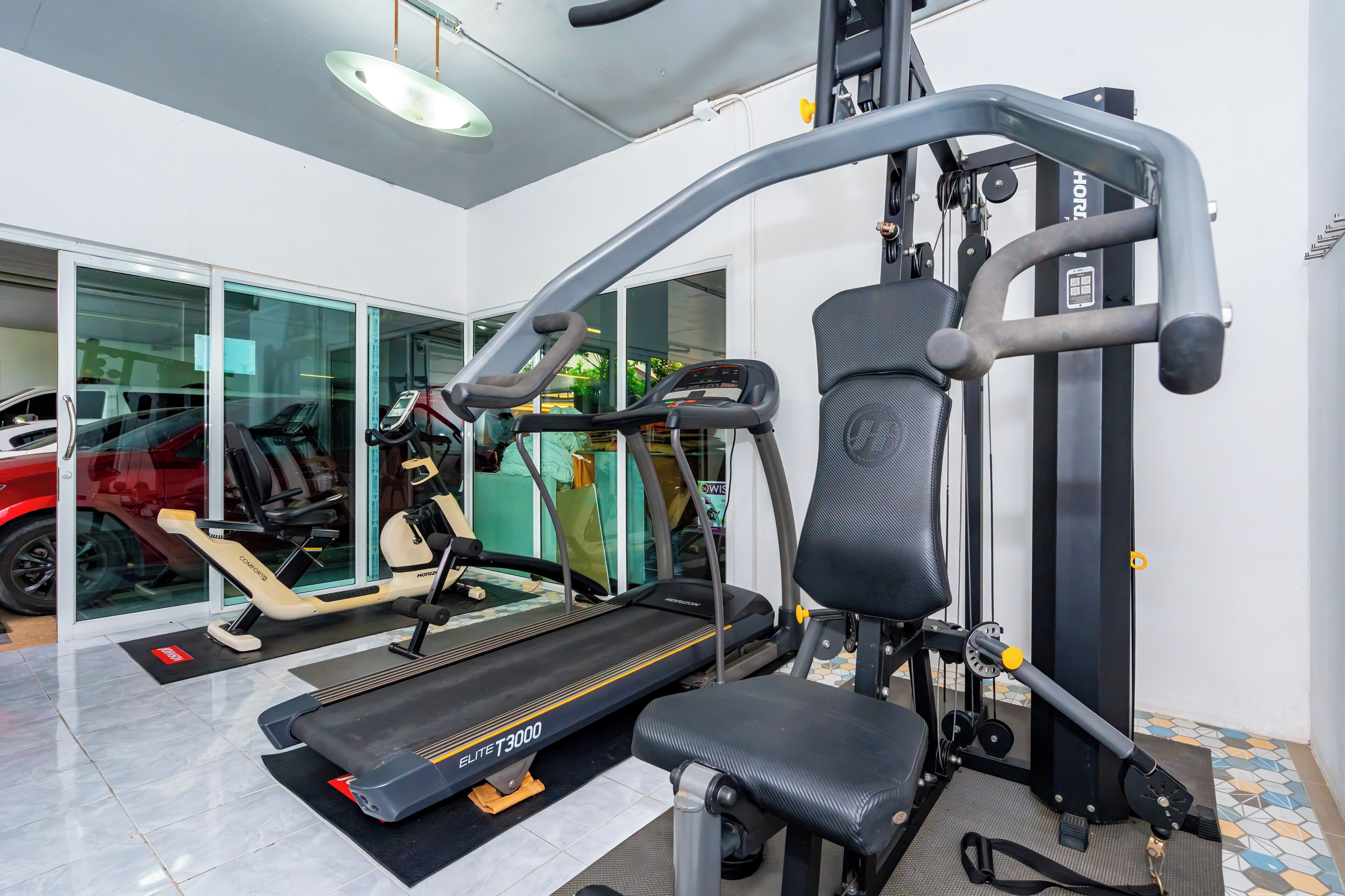 A gym with a treadmill, weight machines, and a bench.