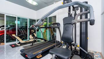 A gym with a treadmill, weight machines, and a bench.