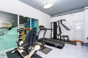 Un gimnasio con elíptica, cinta de correr y máquinas de pesas.