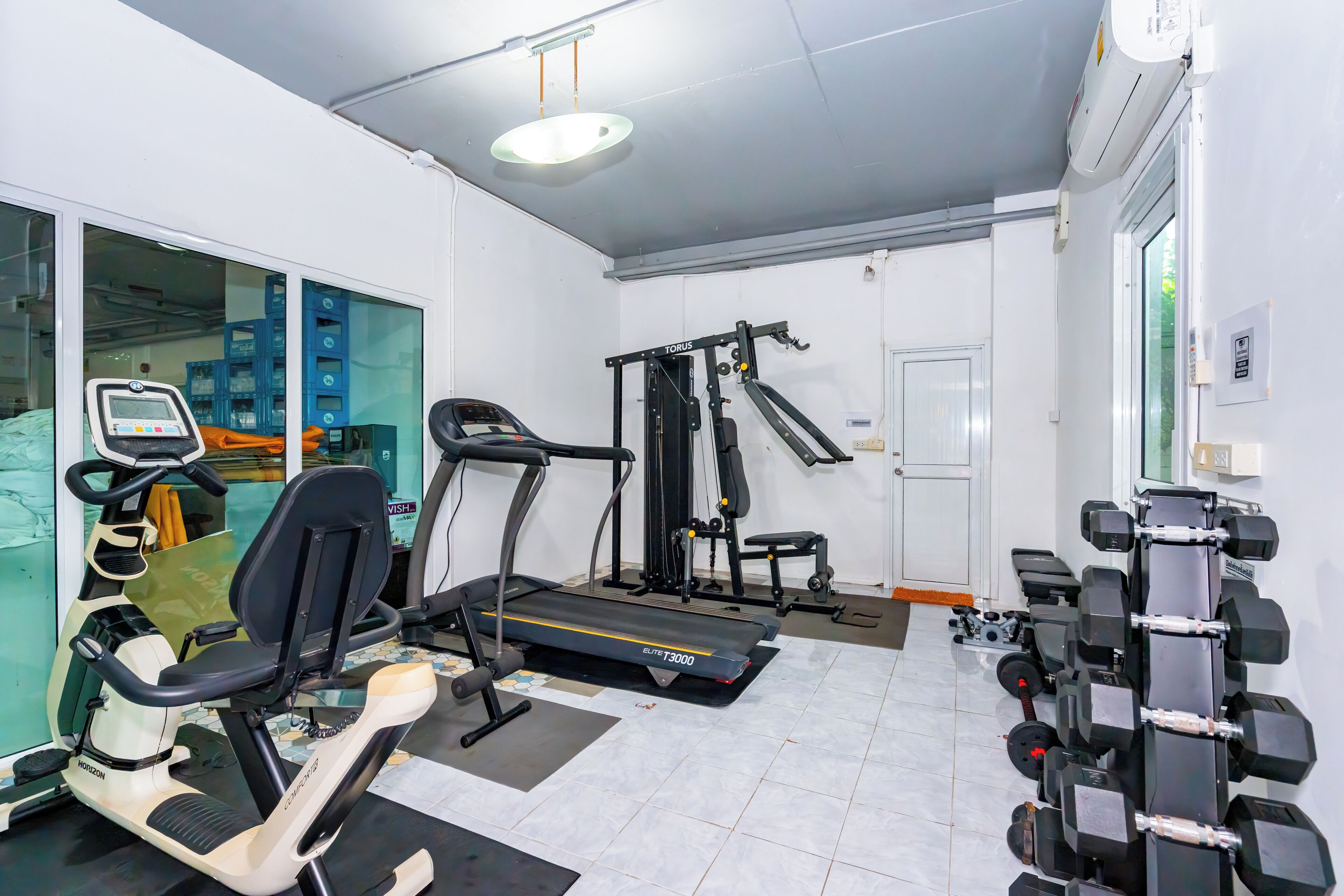 A gym with exercise equipment including a treadmill, elliptical, and weight machines.
