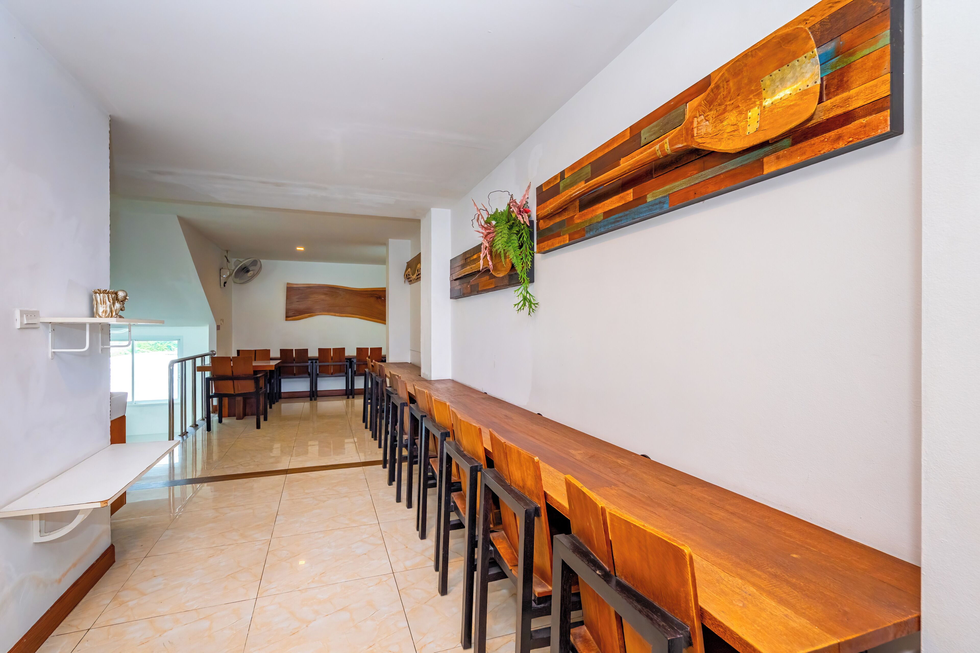 A long wooden table with chairs, a white reception desk, and a wall-mounted wooden artwork.