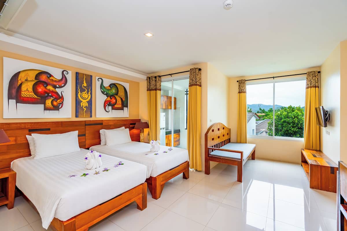 A hotel room with two beds, a wooden headboard, a TV, and a window with a view.