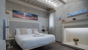 Un dormitorio moderno con cama, mesita de noche, un jarrón de flores y obras de arte en las paredes.