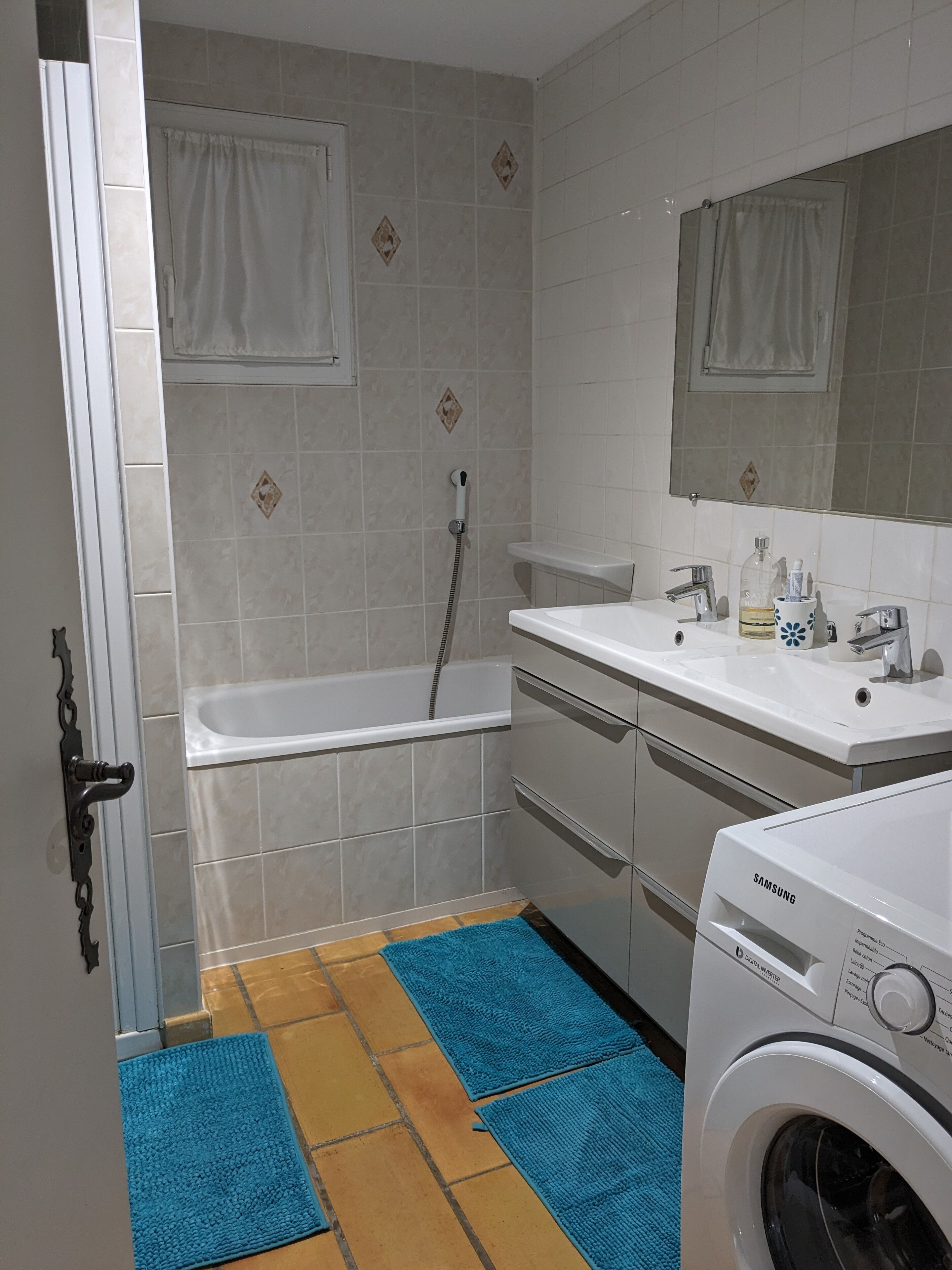 A bathroom with a bathtub, a sink, a mirror, and a washing machine.