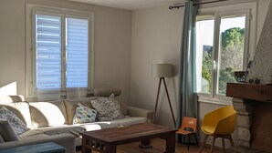 Ein Wohnzimmer mit einer Couch, einem Holztisch, einem gelben Sessel und einem Kamin.
