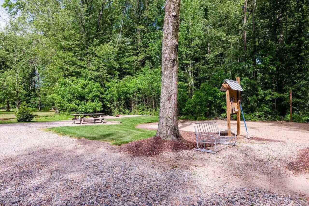 A park with a picnic table, a swing set, and a wooden structure.