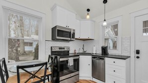 Een moderne keuken met witte kastjes, roestvrijstalen apparatuur en een zwart aanrecht.