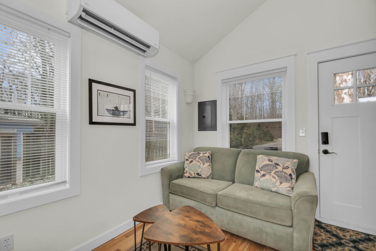 A living room with a green sofa, two wooden coffee tables, and a framed picture on the wall.