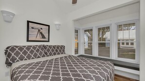 Een slaapkamer met een bed, een ingelijst schilderij aan de muur en een raam met zonwering.