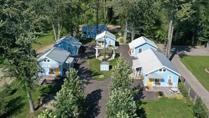 Een groepje blauwe huisjes met aanbouwen, omringd door bomen.