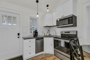 A compact kitchen with white cabinetry, a built-in microwave, and an oven.
