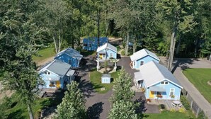 A cluster of blue cabins surrounded by trees, with a central path connecting them.