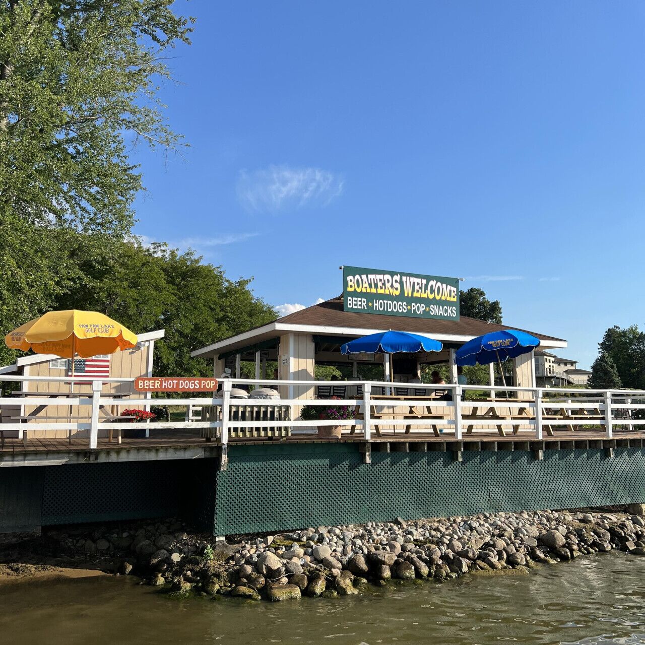 A waterfront restaurant with a sign reading "Boaters Welcome" and amenities listed as beer, hotdogs, and pop snacks.