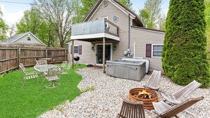 Una casa de dos pisos con un patio, mobiliario exterior y un brasero.