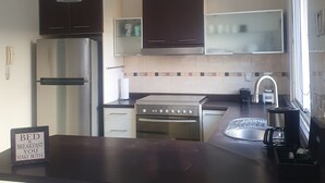 A modern kitchen with stainless steel appliances, dark cabinets, and pendant lighting. - México City Luxory Apartment for 6. (Ciudad de México)