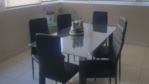A dining area with a glass table and black chairs, a potted plant, and a ceiling light fixture. - México City Luxory Apartment for 6. (Ciudad de México)