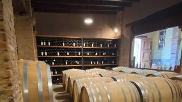 A wine cellar with wooden barrels and shelves of wine bottles.