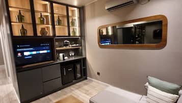Uma sala de estar moderna com um sofá, uma mesa de centro e uma área de cozinha com televisão.