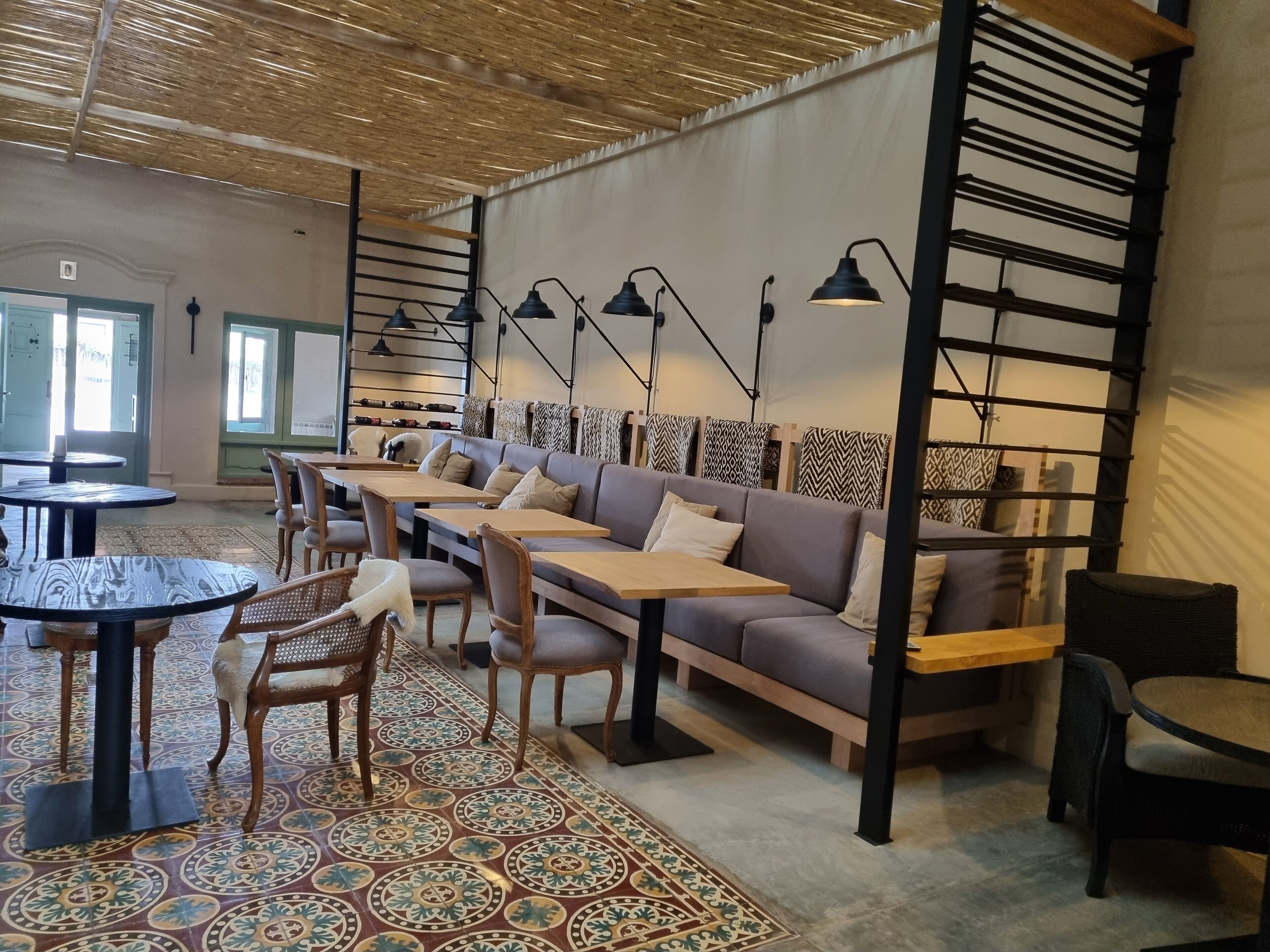 Ein modernes Interieur mit einem gemusterten Boden, Holztischen und einem grauen Sofa.