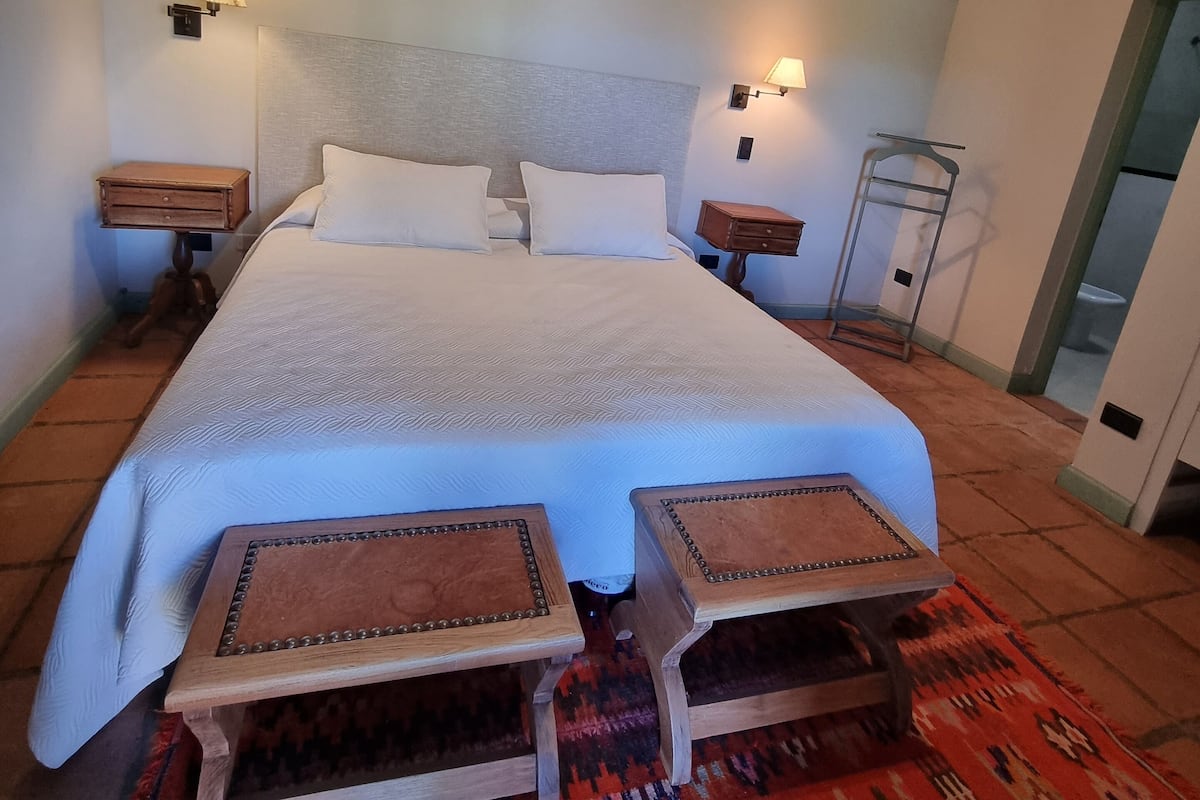 Ein geräumiges Schlafzimmer mit einem großen Bett, zwei Nachttischen und einem Schminktisch.