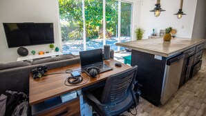 Een moderne keuken met een groot eiland, een zithoek met een bank en een aan de muur bevestigde televisie.
