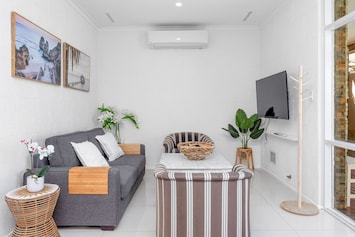 Relax and unwind in our cozy living area, perfect for lounging after a day of exploring! Sink into the comfortable sofa, enjoy your favorite shows on the wall-mounted Smart TV, and stay cool with the efficient air conditioning.